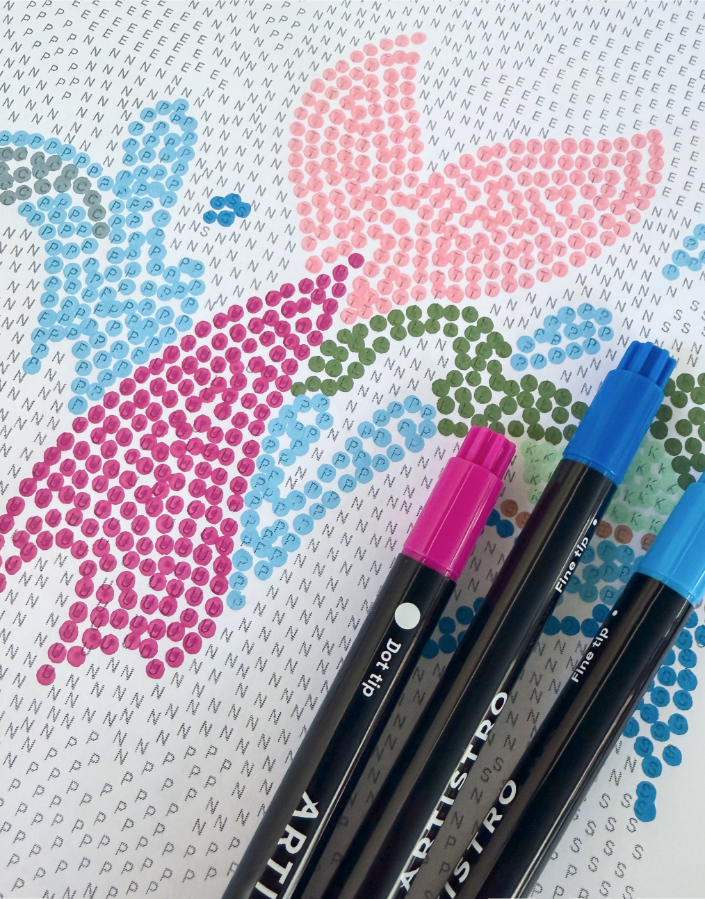 A dot-by-letter page part-way colored in, with Artistro dot markers resting on top